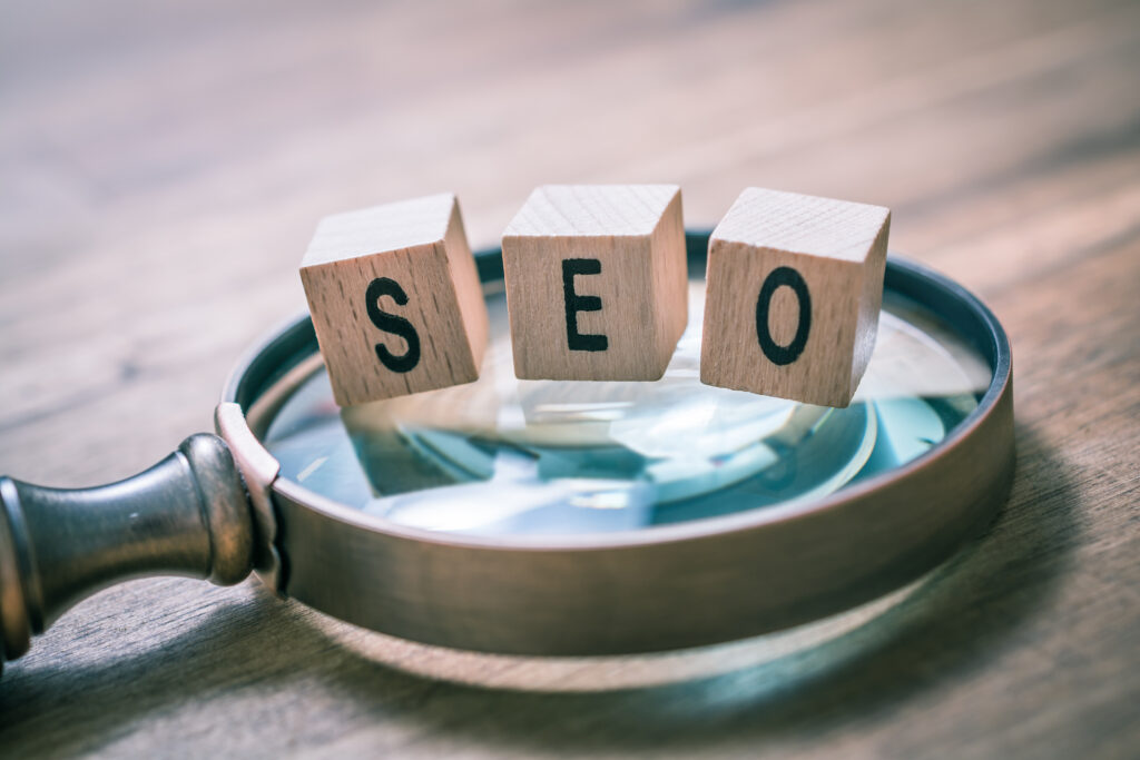 Blocs de bois avec les lettres SEO posés sur une loupe