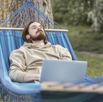 Un homme relaxant dans un hamac en travaillant sur son ordinateur portable